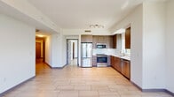 Located at 6445 NE Seventh Ave in Miami's vibrant Little Haiti neighborhood, this contemporary 2-bedroom, 2-bathroom residence offers a thoughtfully designed single-floor layout with a clean, modern aesthetic throughout. Large-format light tile flooring flows seamlessly across every room, creating a cohesive and airy feel.

The open-concept kitchen is well-appointed with warm wood-grain cabinetry, white quartz countertops, a herringbone tile backsplash, and a full suite of stainless steel appliances including a refrigerator, range, microwave, and dishwasher. Natural light enters through a dedicated kitchen window with neighborhood views.

The living area is bright and spacious, anchored by floor-to-ceiling sliding glass doors that open to a balcony, offering lush tree-top views. The dining area sits adjacent, creating a natural flow for entertaining.

The generously sized primary bedroom features built-in closet spaces, a window with greenery views, and a ceiling fan. The second bedroom is equally bright, with a wide horizontal window framing outdoor scenery. Both bathrooms are finished in a clean, contemporary style with wood-grain vanities, white quartz countertops, and tub-shower combinations with white tile surrounds.

A functional hallway connects the bedrooms and includes utility access, completing this well-organized and stylish Miami residence.