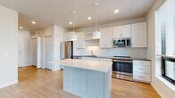 Located at 508 W Washington Ave in downtown Madison, Wisconsin, this single-floor unit offers a clean, modern aesthetic defined by bright white walls, light wood-style flooring, and an open layout that promotes a sense of spaciousness throughout.

The kitchen serves as the centerpiece of the living area and is outfitted with white shaker-style cabinetry, a herringbone tile backsplash, dark countertops, and a full suite of stainless steel appliances including a refrigerator, range, microwave, and dishwasher. A central island with a white quartz surface and pendant lighting above provides additional workspace and a natural gathering point. Open shelving adds both function and visual interest to the kitchen design.

The living area benefits from a generous bank of large windows fitted with horizontal blinds, allowing ample natural light while offering views of the surrounding urban streetscape. Light wood-style flooring runs consistently throughout, lending warmth and continuity to the space.

A sliding barn door adds a contemporary architectural detail and provides access to additional rooms. The bathroom features a gray shaker-style vanity with gold hardware, white countertop, a framed mirror, and a glass-enclosed shower. The entry area includes a built-in bench, adding practical storage and organization at the front of the unit.