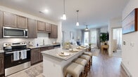 This single-floor, 2-bedroom, 2-bathroom residence offers a thoughtfully designed open-concept layout that maximizes its well-proportioned footprint. The kitchen and living area flow seamlessly together, anchored by a large granite-topped island with seating for multiple guests. The kitchen is outfitted with rich dark-wood cabinetry, a classic white subway tile backsplash, stainless steel appliances including a refrigerator, range, microwave, and dishwasher, and elegant pendant lighting overhead. Wood-look flooring extends throughout the main living areas, complementing the neutral color palette.

The living room receives natural light through large windows dressed with sheer curtains and blinds, and features a ceiling fan. The primary bedroom is a comfortable, well-lit retreat with natural light, a ceiling fan, and access to a dedicated bathroom with a granite-topped vanity, a glass-enclosed shower, and a spacious walk-in closet equipped with wire shelving. The second bedroom is equally bright, also featuring a ceiling fan and natural light. Both bedrooms are finished with plush carpeting, contributing to a warm, functional living environment throughout.