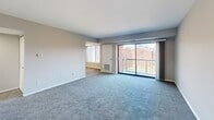 Located at 155 E Godfrey Ave in Philadelphia's 19120 neighborhood, this two-bedroom, one-bathroom residence offers a practical and well-organized single-floor layout. The open living area is carpeted in a neutral blue-gray tone and features large sliding glass doors that lead to a private balcony with outdoor views of the surrounding brick buildings and greenery, allowing ample natural light to fill the space. A secondary living area connects seamlessly, providing flexibility for dining or additional lounge space. The kitchen is outfitted with gray shaker-style cabinetry, white countertops, a stainless steel sink, and a full-size stainless steel refrigerator, complemented by wood-look luxury vinyl flooring and a window overlooking the exterior. The primary bedroom is generously sized, featuring carpet flooring, a wide built-in closet with double doors, and good natural light. The second bedroom also offers carpet flooring and a large window with blinds. Both bedrooms are finished in neutral gray tones. The bathroom includes a full tub-shower surround with built-in shelving and classic white tile accents. A connecting hallway ties all rooms together efficiently, completing this straightforward and functional residential layout.