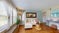 Located in Bradenton, FL, this 2-bedroom, 3-bathroom single-floor residence offers a thoughtfully designed layout with a warm coastal aesthetic throughout. The open living area features wood-look flooring, a textured ceiling, and large windows that flood the space with natural light while offering pleasant outdoor views. A seamless connection to the kitchen makes the area ideal for everyday living and entertaining.

The kitchen is well-equipped with light wood cabinetry, dark granite-style countertops, black appliances, and a peninsula that doubles as a dining bar. A pendant light and a window overlooking the exterior add both function and brightness to the space.

Both bedrooms are carpeted and comfortably sized, with the primary bedroom offering a ceiling fan, a sliding glass door with outdoor views, and direct access to a dedicated closet area. The second bedroom also features a ceiling fan and ample closet storage with louvered bifold doors.

All three bathrooms maintain a consistent style, with wood-look flooring, tub-shower combinations, and dark countertop vanities. Each bathroom reflects the home's cohesive coastal theme.

A connecting hallway links all rooms efficiently, contributing to a functional and well-organized floor plan. Throughout the residence, coastal-inspired accents and neutral tones create a relaxed, inviting ambiance well-suited to the Florida lifestyle.