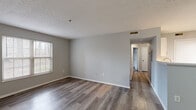 Located at 607 Worthington Forest Pl in Columbus, OH, this two-bedroom, one-bathroom unit offers a practical and well-organized single-floor layout. The combined kitchen and living area serves as the heart of the home, featuring a peninsula with a light-toned countertop and a brushed gold faucet. The kitchen is equipped with stainless steel appliances, including an electric range and refrigerator, white cabinetry, and track lighting overhead. Light wood-style vinyl flooring runs through the kitchen and living areas, contributing to a clean, cohesive look. The spacious living room benefits from natural light through a side window and connects seamlessly to the hallway leading to the bedrooms. The primary bedroom is generously sized, featuring dark hardwood-style flooring, neutral gray walls, and a window with outdoor views. It includes access to a walk-in closet with wire shelving on multiple walls and carpeted flooring for added comfort. The second bedroom is carpeted and also features a window that brings in natural light. The full bathroom includes a tub-shower combo, a white vanity with sink, and wood-style flooring. Two hallways connect the rooms efficiently, and the overall neutral palette creates a calm, move-in-ready atmosphere throughout.