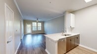 This contemporary 1-bedroom apartment in Charleston, SC offers 660 square feet of efficiently designed living space. The open floor plan creates a seamless flow between the living areas, optimizing the use of space. The kitchen is a standout feature, boasting sleek white cabinetry, stainless steel appliances, and a practical island with a sink, perfect for food preparation or casual dining.

The spacious bedroom, measuring 180 square feet, is equipped with a ceiling fan and large windows that flood the room with natural light. The bathroom is elegantly appointed with a modern vanity, large mirror, and a combination tub-shower unit. High-quality laminate flooring runs throughout the apartment, providing a cohesive and low-maintenance surface.

Additional features include ample closet space with wire shelving, energy-efficient windows with blinds, and crown molding that adds a touch of sophistication. The neutral color palette allows for easy personalization. Located at 480 Seven Farms Drive, this apartment offers a blend of comfort and style in a prime Charleston location.