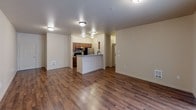 This single-floor unit at 10436 SE Carr Rd, Unit B304, in Renton, Washington offers a thoughtfully designed layout with a clean, neutral aesthetic throughout. The open-concept living area is anchored by warm hardwood-style flooring that extends seamlessly from the spacious main room into the kitchen zone, creating a cohesive and inviting common area. Flush-mount ceiling fixtures provide consistent lighting throughout the unit.

The kitchen features a galley-style configuration with rich wood cabinetry, gray laminate countertops, a double-basin stainless steel sink, and a full suite of appliances including an electric range, microwave, refrigerator, and dishwasher. A peninsula counter separates the kitchen from the living area, offering both additional prep space and a natural transition between rooms.

The bedrooms are carpeted for comfort and offer ample wall space, with one room featuring a window with views of surrounding greenery. Closet space is present in the bedrooms, including a reach-in closet with a hanging rod. A dedicated hallway connects the private areas of the unit, with access to bathroom facilities visible from the bedroom corridor.

Overall, the unit presents a clean, functional, and comfortable living environment with a neutral color palette, practical storage solutions, and durable finishes suited for everyday living.