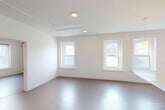 Located at 187 Pearl St in the heart of Burlington, Vermont, this three-bedroom, one-bathroom unit offers a compact yet functional single-floor layout. The living area is bright and welcoming, featuring multiple large windows that frame views of the surrounding Burlington cityscape, allowing natural light to fill the space throughout the day. Baseboard heating runs along the walls, providing warmth during Vermont's colder months.

The kitchen is efficiently designed with light wood cabinetry extending to the ceiling for ample storage, a white electric range, and standard appliances. The layout makes practical use of every inch of available space.

Each of the three bedrooms offers a distinct character. The primary bedroom features large windows with generous natural light and a classic wrought-iron bed frame. A second bedroom benefits from bright window exposure, while the third is a cozier, more intimate space. Each bedroom includes dedicated closet storage, and three closets are found throughout the unit.

The shared bathroom is clean and straightforward, featuring a shower-tub combination with a curtain, a toilet, and open wire shelving for toiletry storage. Flooring throughout the unit consists of hardwood-style surfaces in the main areas. The unit's location in downtown Burlington provides convenient access to local amenities, dining, and the broader community.