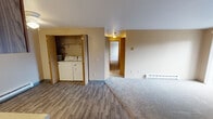 Located at 14901 SE 272nd St in Kent, Washington, this single-floor residential unit offers a functional and comfortable layout across several well-defined living spaces. The carpeted living room serves as the centerpiece of the home, anchored by a tile-surround fireplace and a sliding glass door that opens to a private balcony, allowing natural light to fill the space and providing views of the surrounding greenery. The galley-style kitchen is efficiently designed with warm wood cabinetry lining both sides, white appliances including an electric range, dishwasher, and refrigerator, and light-toned countertops over durable vinyl plank flooring. An adjacent dining area with a baseboard heater and overhead light offers a casual space for meals. The bedrooms are carpeted and benefit from natural light through vertical-blind-covered windows, each equipped with baseboard heating. A dedicated laundry closet with a full-size washer and dryer adds significant convenience. The unit includes two full bathrooms, each featuring a tub-shower combination with chrome fixtures — one with a vanity and stone-look countertop and large mirror. Throughout, neutral wall tones and wood-trimmed doors contribute to a cohesive, understated aesthetic.