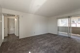 Located at 859 N Mountain Ave in Upland, California, this single-floor residence offers a clean, well-maintained layout designed for comfortable living. The living area is generously sized, featuring plush wall-to-wall carpeting, crisp white walls, and a sliding glass door fitted with vertical blinds that opens to an outdoor balcony, allowing natural light to fill the space. The bedroom areas are similarly appointed with soft carpeting and vertical blind-covered windows that provide ample daylight and outdoor views. The galley-style kitchen is a standout feature, showcasing white shaker cabinetry with brushed gold hardware, quartz-style countertops, recessed lighting, wood-look luxury vinyl plank flooring, and a full suite of white appliances including a range, oven, refrigerator, and dishwasher. The bathroom presents a long, functional vanity corridor with white cabinetry, brushed gold fixtures, a quartz countertop, a large mirror, and wood-look flooring leading to a dedicated shower and tub area. Throughout the residence, the neutral color palette and consistent finishes create a cohesive, light, and airy ambiance well-suited for everyday living.