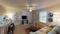 Located at 922 N Sidney Ave in Russellville, Arkansas, this single-floor residence offers a thoughtfully arranged layout designed for comfortable everyday living. The living room serves as the heart of the home, featuring plush carpeting, a ceiling fan with light fixture, and windows dressed with blinds that allow natural light to fill the space. The room provides ample space for seating and entertainment, with neutral wall tones creating a warm, welcoming atmosphere. The kitchen is designed in a galley style and connects seamlessly to a peninsula with bar seating, making it ideal for casual dining and interaction. Light wood cabinetry lines both walls of the kitchen, complemented by hardwood-style flooring, a coil-top electric range, refrigerator, and dishwasher. The bedroom is a restful retreat, complete with carpeted flooring, a ceiling fan, and a window that brings in soft natural light. The textured ceiling carries throughout the unit, adding a consistent design element to each room. The bathroom features hardwood-style flooring, a single-sink vanity with wood cabinetry, a large mirror, and overhead lighting, offering a clean and functional space. Overall, the residence presents a cozy and practical living environment in a convenient Russellville location.