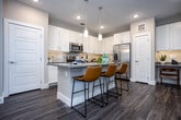 Located at 1980 Icon Way in Knoxville, Tennessee, this single-floor residence offers a thoughtfully designed layout with modern finishes throughout. Rich wood-look flooring flows seamlessly across all living areas, anchoring the contemporary aesthetic.

The open-concept kitchen is a standout feature, showcasing crisp white shaker cabinetry, gray quartz countertops, a full suite of stainless steel appliances, and a subway tile backsplash. A large center island with pendant lighting and bar seating makes it ideal for both cooking and casual dining. A dedicated built-in desk area adjacent to the kitchen provides a convenient workspace.

The living room is bright and welcoming, with large windows that invite natural light and offer outdoor views. The bedrooms are comfortably scaled, each featuring large windows, dark hardwood-style flooring, and ceiling fans. The primary bathroom impresses with a dual-sink vanity, white cabinetry, gray quartz countertops, and backlit LED mirrors, with direct access to the bedroom. A secondary full bathroom mirrors the same clean, modern design. A hallway laundry area and smart home thermostat add practical convenience. The overall ambiance is polished, cohesive, and move-in ready.