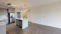 Located at 5500 Home Valley Dr in Raleigh, NC, this single-floor residence offers a thoughtfully designed, open-concept layout with contemporary finishes throughout. The kitchen serves as a central hub of the home, featuring a large island with a white quartz countertop, undermount sink, and pendant lighting above. Flat-panel cabinetry in a warm wood-tone finish lines the walls alongside a classic subway tile backsplash, and stainless steel appliances — including a refrigerator with ice maker, electric range, microwave, and dishwasher — complete the space. An in-unit washer and dryer are conveniently located just off the kitchen. Rich, dark hardwood-style flooring flows throughout the main living and kitchen areas, lending warmth and cohesion to the open floor plan. The living area is generously proportioned, benefiting from abundant natural light. The bedroom is finished with plush carpeting, a ceiling fan, and a wide window fitted with horizontal blinds, providing a comfortable and quiet retreat. The bathroom is well-appointed with large-format tile flooring, a soaking tub with tiled surround, a wood-tone vanity with a light countertop, and a walk-in closet accessible directly from the bathroom. The overall aesthetic is clean, modern, and move-in ready.