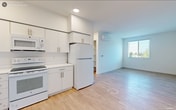 Located at 1520 Hecker Pass Hwy in Gilroy, California, this single-floor, 3-bedroom, 2-bathroom unit offers a clean and modern living environment with a thoughtfully designed layout. Light wood-style flooring flows consistently throughout the space, complementing the crisp white walls and creating a bright, cohesive aesthetic.

The kitchen is well-appointed with white cabinetry extending to the ceiling for ample storage, white appliances including a range, microwave, refrigerator, and dishwasher, recessed lighting, and a functional countertop workspace. It opens conveniently toward the living area, enhancing the sense of openness.

Each of the three bedrooms features light flooring and neutral walls. The primary bedroom includes a wall-mounted mini-split unit for individual climate control. Several bedrooms offer windows with views of surrounding greenery, filling the rooms with natural light.

The two bathrooms maintain the same clean, white design language. One includes a tub-shower combination with tiled surround and a single-sink vanity with white cabinetry. The second bathroom features accessibility-friendly grab bars and a spacious vanity. Both bathrooms are finished with light wood-style flooring.

Additional spaces include an entrance, hallway, and two closets. The overall ambiance is modern, minimalist, and move-in ready.