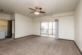 Located at 150 Rapids Square in Waterloo, Iowa, this well-appointed 2-bedroom, 1-bathroom residence offers a thoughtfully designed single-floor layout with a clean, modern aesthetic throughout. The open-concept kitchen and living area forms the heart of the home, where rich dark cabinetry with granite-style countertops pairs with wood-look tile flooring and black appliances — including a refrigerator, range, and dishwasher — to create a functional and stylish culinary space. The living area flows naturally from the kitchen, featuring plush carpeting, a ceiling fan with integrated lighting, and a sliding glass door that opens onto a private balcony with outdoor views. Both bedrooms are comfortably sized and carpeted, offering neutral tones and dark-trimmed doors. The primary bedroom is generously proportioned and includes a dedicated closet, while the second bedroom features a bright window with garden views. Four closets throughout the home provide ample storage. The full bathroom includes a vanity with dark cabinetry, a tub-shower combo, and wood-look tile flooring. A dedicated in-unit laundry room with a full-size washer and dryer adds everyday convenience. The space is finished with consistent dark baseboards and door trim, giving the interior a cohesive, polished look.