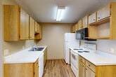 Located at 4500 E 33rd St in Sioux Falls, South Dakota, this two-bedroom, one-bathroom residence offers a well-organized single-floor layout with a practical and comfortable design throughout. The open-concept main area seamlessly connects the living room, dining space, and kitchen, with warm-toned walls, plush carpeting in the living area, and durable wood-style flooring in the kitchen. A chandelier serves as a focal point above the dining area, adding a touch of elegance to the shared space. The galley-style kitchen is efficiently designed with ample honey-toned oak cabinetry on both sides, white appliances including a range, refrigerator, and built-in microwave, plus a double sink with white countertops. Both bedrooms feature soft carpeting, textured ceilings, baseboard heating, and windows with blinds that allow natural light while providing privacy. The primary bedroom is generously sized and includes two closets. The full bathroom is finished with tile flooring and features a full tub-shower combination with a grab bar. Additional storage is provided by four closets spread throughout the unit. A private balcony extends the living space outdoors, offering a pleasant retreat. The hallway connects all rooms efficiently, completing this functional and inviting floor plan.