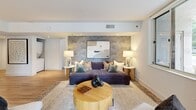 Located at S Eads St in Arlington, VA, this well-appointed two-bedroom, one-bathroom residence offers a thoughtfully designed single-floor layout with a comfortable and cohesive sense of space. Light hardwood flooring flows throughout, complementing the clean, contemporary aesthetic.

The living room serves as the heart of the home, featuring a striking botanical wallpaper accent wall, recessed lighting, and sliding glass doors that open directly onto a private patio with urban views. Natural light pours in through multiple windows, creating a bright and welcoming atmosphere.

The kitchen is sleek and modern, outfitted with white cabinetry, quartz countertops, stainless steel appliances including a gas range, and a peninsula with an undermount sink. Large windows overlook the streetscape, adding an airy quality to the space.

The primary bedroom is generously sized, featuring neutral toned walls, hardwood floors, recessed lighting, and ample room for a full furniture suite. The second bedroom offers a charming floral wallpaper accent wall, large windows with lush outdoor views, and warm, inviting character.

The bathroom is clean and minimalist, with white finishes and modern fixtures. Every room reflects a carefully curated, contemporary design sensibility that balances style and everyday functionality.