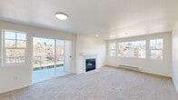 This well-appointed 2-bedroom, 2-bathroom single-floor residence offers a thoughtfully designed layout that balances comfort and functionality. The living room serves as the heart of the home, featuring a tile-surround fireplace, plush wall-to-wall carpeting, and an abundance of natural light through large windows that frame pleasant outdoor views of the surrounding neighborhood. Sliding glass doors open directly to a private balcony, seamlessly connecting indoor and outdoor living. The galley-style kitchen is efficiently arranged with white cabinetry, white appliances including a range, dishwasher, and refrigerator, complemented by light wood-look flooring and a window that brings in natural light. Both bedrooms are carpeted and generously proportioned, each offering windows with neighborhood views and baseboard heating. The primary bedroom includes dedicated closet space. The two bathrooms feature light wood-look flooring and full tub-shower combinations with chrome fixtures. A hallway connects the bedrooms and bathrooms, with additional closet storage available throughout. The unit maintains a clean, neutral color palette of white and warm beige tones, creating a bright and welcoming atmosphere throughout.