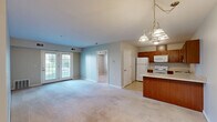 Located at 2880 Transit Rd in Buffalo, NY, this single-floor, 2-bedroom, 1-bathroom residence offers a practical and comfortable layout. The open-concept living and kitchen area serves as the heart of the home, where soft wall-to-wall carpeting in the living room transitions to tile flooring in the kitchen. A pendant chandelier anchors the dining area, while a set of glass patio doors floods the living space with natural light and provides outdoor access. The kitchen is outfitted with warm-toned wood cabinetry, light countertops, a peninsula with breakfast bar seating, and white appliances including a range, refrigerator, microwave, and dishwasher. Both bedrooms feature neutral carpet, soft gray walls, and windows with blinds that allow in natural light. The primary bedroom offers a comfortable footprint with direct hallway access to the shared bathroom and a closet for storage. The full bathroom is finished with tile flooring, a wood vanity with storage, a lighted mirror, and a tub/shower combination. Clean, neutral tones throughout the residence create a bright, move-in-ready atmosphere well suited for everyday living.