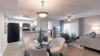 This single-floor residence offers a cohesive, contemporary design with wood-style flooring, textured ceilings, and ceiling fans featured throughout. The living room serves as a welcoming focal point, anchored by a large sliding glass door with vertical blinds that opens to a private balcony overlooking lush palm tree surroundings, filling the space with natural light.

Adjacent to the living area, the dining space connects seamlessly to the kitchen via a pass-through bar counter. The kitchen is well-equipped with white cabinetry, granite-style countertops, a subway tile backsplash, and black Whirlpool appliances, including a refrigerator, range, and microwave.

The residence features multiple bedrooms, each with ceiling fans, natural light from large windows, and generous closet space. One bedroom is accented with a bold teal feature wall, while others maintain neutral tones. Each room benefits from direct access to a bathroom, with at least one bathroom showcasing wood-style flooring, a white vanity with a light countertop, and a large mirror. A dedicated closet area provides additional storage, completing this functional and attractively designed home.