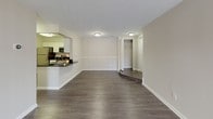 This single-floor residence offers a thoughtfully designed layout with a clean, neutral palette that creates a bright and welcoming atmosphere throughout. The open-concept living and dining area is anchored by durable dark hardwood-style flooring and is bathed in natural light through a large sliding glass door fitted with vertical blinds, providing direct access to an outdoor area. The space flows seamlessly into the half-wall pass-through kitchen, which features white shaker-style cabinetry, dark granite countertops, and a full suite of stainless steel appliances including a range, over-the-range microwave, and dishwasher. The kitchen's efficient layout maximizes both storage and workspace. Two generously sized bedrooms are finished with plush, light-toned carpeting and feature windows that frame views of the surrounding greenery, filling each room with soft, natural light. A dedicated closet provides ample storage in the main bedroom area. The full bathroom is outfitted with a tub-shower combination, a white vanity with an integrated sink, brushed nickel fixtures, and a well-lit mirror. A second bathroom features dark hardwood-style flooring and a matching vanity. A walk-in closet adds further storage convenience to the unit.
