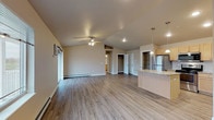 This single-floor residence is thoughtfully designed with an open-concept layout that connects the living area and kitchen, creating a spacious and functional flow. The living area features light wood-look flooring, a ceiling fan, and baseboard heating, with a window-mounted air conditioning unit providing additional climate control. Natural light enters through multiple windows, contributing to a bright and welcoming ambiance.

The kitchen is well-appointed with light maple cabinetry, granite countertops, a tile backsplash, and a full suite of stainless steel appliances including a refrigerator, gas range, and microwave. A peninsula with pendant lighting above provides additional prep space and casual seating opportunities.

The bedrooms are carpeted for comfort and each include a ceiling fan. One bedroom benefits from a window with an outdoor view and baseboard heating. Closet storage is accessible from the main living area as well.

Two bathrooms serve the unit — one featuring a soaking tub with surrounding surround and wood-look flooring, and the other equipped with a walk-in shower stall with built-in shelving. A dedicated in-unit laundry area with overhead wire shelving completes the practical offerings of this well-organized space.
