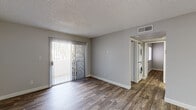This single-floor residence offers a clean, contemporary layout designed for comfortable everyday living. The open living area is finished with durable wood-style flooring and neutral gray walls, creating a bright and versatile space. A ceiling fan provides added comfort, and a sliding glass door with vertical blinds opens to an outdoor area, allowing natural light to flow in. Conveniently tucked nearby, a stacked washer and dryer unit adds in-unit laundry functionality.

The kitchen is well-equipped with white shaker-style cabinetry, granite-look countertops, and a full suite of stainless steel appliances including a refrigerator, range, over-the-range microwave, and a stainless sink. The wood-style flooring continues seamlessly from the living areas into the kitchen.

Two bedrooms each feature the same warm wood-style flooring, neutral walls with a textured ceiling, and individual closets offering practical storage. The bathroom is finished in a clean, all-white palette with a full tub and shower combination, wood-style flooring, a vanity with granite-look countertop, and chrome fixtures throughout. The overall design emphasizes a consistent, modern aesthetic with a neutral color palette that makes the space feel open, functional, and move-in ready.