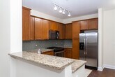 Located along I-80 East in Elmwood Park, NJ, this single-floor residence offers a well-designed open layout with thoughtfully finished interiors throughout. The living area is anchored by rich hardwood flooring and neutral-toned walls, creating a bright and welcoming atmosphere. A window allows natural light to fill the space, offering views of the surrounding exterior.

The kitchen is a functional highlight, featuring warm wood cabinetry extending to the ceiling for generous storage, granite countertops, a classic subway tile backsplash, and a full suite of stainless steel appliances including a gas range, built-in microwave, and French door refrigerator. Track lighting illuminates the workspace effectively. A peninsula counter connects the kitchen to the open living and dining area, enhancing the sense of flow.

The bedroom is carpeted for comfort and includes a window with natural light. The bathroom is finished with a dark espresso wood vanity topped with a light stone countertop, a large mirror, mosaic tile flooring, and clean, neutral wall tones. The overall design is cohesive and modern, balancing practicality with refined finishes throughout.