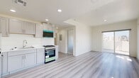 Located at 983 Dewey Ave in Los Angeles, this thoughtfully designed one-bedroom, one-bathroom unit offers a clean, modern aesthetic throughout its single-floor layout. The open-concept living area seamlessly connects the kitchen, dining, and living spaces, all finished with light wood-tone laminate flooring and crisp white walls that maximize brightness.

The kitchen is well-appointed with grey shaker-style cabinetry, white countertops, and a full suite of stainless steel appliances including a refrigerator, dishwasher, gas range, and over-the-range microwave. Recessed lighting illuminates the space, while a marble-look tile backsplash adds a refined touch.

The living area benefits from large sliding glass doors and multiple windows that invite abundant natural light and offer views of the surrounding Los Angeles cityscape and palm trees beyond.

The bedroom is carpeted for comfort and features a mirrored sliding closet door and a window with neighborhood views, creating a bright and restful retreat.

The bathroom stands out with striking floor-to-ceiling marble-patterned wall panels in the walk-in shower, a bold navy blue vanity with chrome hardware, wood-tone flooring, and a frameless glass shower enclosure — combining style and functionality in a compact, well-finished space.