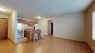 This single-floor unit offers a practical and functional layout designed for comfortable everyday living. The open-concept living and kitchen area forms the heart of the space, where light wood-style flooring extends throughout, creating a bright and cohesive feel. The kitchen is well-equipped with warm oak cabinetry, white appliances including a refrigerator, stove, and dishwasher, and a peninsula island with seating for two — ideal for casual dining or meal prep. A textured ceiling is consistent throughout the unit, adding a classic residential character.

The living area is generously proportioned, offering ample room for a variety of furniture arrangements, with neutral walls providing a versatile backdrop. The bedrooms are well-sized, each featuring the same warm hardwood-style flooring. One bedroom includes a large sliding-door closet providing substantial storage, as well as a window with blinds allowing natural light to filter in, accompanied by a baseboard heater. The second bedroom is clean and compact with easy access to the rest of the unit.

The bathroom is finished with oak vanity cabinetry, a wide countertop with a single sink, a large mirror, and a full tub-shower combination with tiled surround. Tile flooring completes this functional and tidy space.