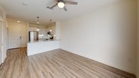 The Impressionist offers a well-appointed 1-bedroom, 1-bathroom apartment spanning 713 square feet of single-floor living. The open-concept layout connects the living area to the kitchen, which features stainless steel appliances including a French door refrigerator, electric range, and over-the-range microwave. White shaker-style cabinetry, a subway tile backsplash, and light wood-look luxury vinyl plank flooring give the kitchen a clean, modern aesthetic. Pendant lighting above the kitchen peninsula adds a refined touch.

The living area is bright and spacious, finished with the same wood-look flooring and a ceiling fan with integrated lighting. A set of floor-to-ceiling glass doors floods the space with natural light and provides outdoor views.

The bedroom continues the open, airy feel with plush carpet, a ceiling fan, and matching glass panel doors that offer additional natural light and outdoor access.

The bathroom is finished with white cabinetry, a wide undermount sink, quartz-style countertops, a large framed mirror, and contemporary light fixtures. Wood-look flooring and ample cabinet storage complete the space. The overall ambiance throughout is clean, modern, and move-in ready.