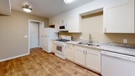 This single-floor residence offers a thoughtfully designed layout with a clean, neutral aesthetic throughout. The kitchen is a functional highlight, featuring white shaker-style cabinetry, light granite countertops, a double basin sink with a brushed nickel faucet, and white appliances including a gas range, microwave, refrigerator, and dishwasher. Wood-look flooring runs through the kitchen and hallway areas, providing durability and visual continuity.

The living area is generously sized, finished with carpet and equipped with a ceiling fan. A sliding glass door opens to a balcony with outdoor views, allowing natural light to fill the space. The bedrooms are carpeted and feature neutral-toned walls, windows with blinds offering outdoor views, and ceiling fans in select rooms.

Two bathrooms serve the residence. One includes a single vanity with a white cabinet base, a large mirror, and wood-look flooring. The second features a soaking tub with built-in shelving, a toilet, and matching flooring. Overall, the space presents a cohesive, move-in ready environment with practical finishes and a calm, neutral color palette throughout.