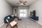 This single-story, 3-bedroom, 2-bathroom home offers a thoughtfully designed layout that balances comfort and functionality throughout. The living room features soft carpeting, a ceiling fan with light fixture, and a full-width sliding glass door that floods the space with natural light and provides direct views of the surrounding neighborhood. The kitchen is well-equipped with dark espresso cabinetry, stainless steel appliances including a refrigerator, range, microwave, and dishwasher, and light-toned countertops, all set over durable wood-look flooring. A dedicated dining area adjoins the kitchen, accented by wood-look flooring and a neutral color palette. The spacious primary bedroom includes a ceiling fan, plush carpeting, and ample room for a full furniture arrangement, complemented by a walk-in closet with wire shelving systems. The secondary bedrooms are carpeted and feature windows that bring in natural light. Both bathrooms are finished with tile flooring, dark vanity cabinetry, and white countertops; one includes a full tub-shower combination. A dedicated laundry area accommodates a full-size washer and dryer with additional shelving overhead. Neutral gray tones and consistent finishes unify the home's clean, modern aesthetic throughout.