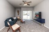 This single-story, 3-bedroom, 2-bathroom home offers a thoughtfully designed layout that balances comfort and functionality throughout. The living room features soft carpeting, a ceiling fan with light fixture, and a full-width sliding glass door that floods the space with natural light and provides direct views of the surrounding neighborhood. The kitchen is well-equipped with dark espresso cabinetry, stainless steel appliances including a refrigerator, range, microwave, and dishwasher, and light-toned countertops, all set over durable wood-look flooring. A dedicated dining area adjoins the kitchen, accented by wood-look flooring and a neutral color palette. The spacious primary bedroom includes a ceiling fan, plush carpeting, and ample room for a full furniture arrangement, complemented by a walk-in closet with wire shelving systems. The secondary bedrooms are carpeted and feature windows that bring in natural light. Both bathrooms are finished with tile flooring, dark vanity cabinetry, and white countertops; one includes a full tub-shower combination. A dedicated laundry area accommodates a full-size washer and dryer with additional shelving overhead. Neutral gray tones and consistent finishes unify the home's clean, modern aesthetic throughout.