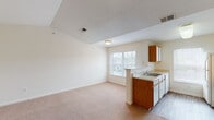 This single-floor residence offers a well-organized layout designed for comfortable everyday living. The open living area flows naturally into the kitchen, which is equipped with warm wood-toned cabinetry, white appliances including a refrigerator, electric range, and dishwasher, ample counter space, and a stainless steel sink. Wood-look flooring runs through the kitchen, while soft neutral carpeting extends throughout the living areas and bedrooms, creating a cohesive and inviting atmosphere. A peninsula-style breakfast bar separates the kitchen from the living space, and windows along the front of the unit invite natural light throughout.

The bedrooms are generously proportioned, with plush carpeting underfoot. The primary bedroom features vaulted ceilings, a ceiling fan, and access to a walk-in closet, lending the room an airy, spacious feel. Additional bedrooms are well-sized with ample natural light from windows with blinds. The bathrooms are finished with wood-look flooring, full soaking tub and shower combinations, vanities with storage, and convenient built-in linen closets with wire shelving. A dedicated in-unit laundry room accommodates a full-size washer and dryer side by side, complete with overhead wire shelving for added storage convenience.
