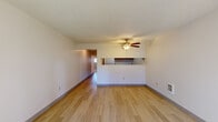 This single-floor residence offers a practical and functional layout designed for comfortable everyday living. The spacious living area serves as the heart of the unit, featuring light wood-style flooring, neutral painted walls, a textured ceiling, and a ceiling fan with a built-in light fixture that promotes airflow and ambient lighting. A wall-mounted heating unit provides additional climate control. The living area connects directly to a pass-through kitchen, which is equipped with warm-toned wood cabinetry, laminate countertops, a stainless steel sink, and dedicated appliance space, making efficient use of the available area. A hallway leads to the private areas of the unit, including bedrooms finished with plush carpeting, textured ceilings, and sliding-door closets that offer generous storage. The full bathroom features a clean, all-white aesthetic with a tub and shower combo fitted with chrome fixtures, a vanity with under-sink cabinetry, and tile-style flooring. Throughout the unit, a consistent neutral color palette of whites and soft grays creates a bright, airy atmosphere. The thoughtful floor plan, as visible in the dollhouse view, ensures a logical flow between the living, kitchen, and sleeping areas, making the space versatile and easy to personalize.