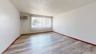 Located at 8101 46th Ave N in New Hope, Minnesota, this single-floor unit offers a practical and well-organized layout throughout. The living area is generously sized, featuring light wood-look flooring, a textured ceiling, and a large picture window dressed with vertical blinds that allows abundant natural light to fill the space. A wall-mounted air conditioning unit and baseboard heating ensure year-round comfort.

The dining area is defined by a elegant chandelier overhead, continuing the same wood-look flooring found throughout the unit, creating a cohesive, open feel between the main living spaces.

The galley-style kitchen is efficiently designed with warm, rich wood cabinetry lining both walls, providing ample storage. It includes a white electric range, a full-size refrigerator, a double basin sink with laminate countertops, and a dedicated pantry closet, making it a highly functional cooking space.

The bedroom offers a clean, neutral aesthetic with white walls, wood-look flooring, bold red baseboards, and a set of full-height bi-fold closet doors for generous storage.

The bathroom features classic mosaic tile flooring, a white vanity, and a tiled shower-tub combination framed by warm wood-toned door trim, lending a timeless character to the space.