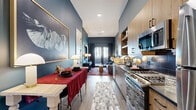 Located at 3963 Walnut St in Denver's vibrant 80205 corridor, this well-appointed one-bedroom, one-bathroom residence makes a strong design statement through bold teal accent walls, warm wood tones, and curated finishes throughout. The galley-style kitchen is efficiently organized with light wood cabinetry, open shelving, dark tile backsplash, dark countertops, and a full suite of stainless steel appliances including a gas range, dishwasher, microwave, and refrigerator. The kitchen flows seamlessly into a dining area and living room, where large framed artwork adorns the teal walls and French doors at the far end draw in natural light. The bedroom continues the deep teal palette, featuring a large window with urban views, a ceiling fan, and generous wall space for art display. The bathroom is finished with a light wood vanity, dark stone countertop, and modern globe light fixture, opening directly into a dedicated walk-in closet with built-in shelving and hanging storage. Light wood-style flooring runs throughout the unit, tying the spaces together. Recessed lighting and carefully placed accent lamps maintain a warm, sophisticated ambiance across every room.