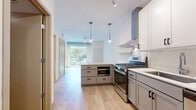 Located at 657 22nd Avenue Northeast in Minneapolis, MN, this thoughtfully designed 2-bedroom, 2-bathroom unit offers a clean, modern aesthetic throughout its efficiently utilized single-floor layout. Light wood flooring flows seamlessly across every room, creating a warm and cohesive atmosphere.

The open-concept kitchen is a standout feature, equipped with stainless steel appliances including a gas range, refrigerator, and dishwasher. A striking blue kitchen island with a white quartz countertop anchors the space, complemented by white upper cabinetry, open wood shelving, and a stainless steel wall-mounted range hood. Pendant lighting overhead adds a contemporary touch, while a large window at the end of the living area floods the space with natural light and offers views of the surrounding greenery.

Both bedrooms are bright and clean, with the primary bedroom featuring a large floor-to-ceiling window that frames an outdoor tree-lined view. The second bedroom provides direct access to one of the two bathrooms. Each bathroom is finished with dark-cabineted vanities, white countertops, and a full tub-shower combination. A dedicated entrance area and closet complete the practical layout of this well-appointed unit.