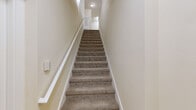 Located at 225 Sunlight Ln in Lake Mary, FL, this two-story, two-bedroom, two-bathroom home offers a functional and comfortable layout across two levels. The main living area is situated on the upper floor, where the majority of the living space is found. Carpet flooring flows throughout the bedrooms and living areas, while tile covers the kitchen and laundry room. The kitchen is well-appointed with warm wood cabinetry, dark granite countertops, stainless steel appliances including a refrigerator, electric range, built-in microwave, and dishwasher, all illuminated by track lighting overhead. Both bedrooms are generously sized, featuring ceiling fans, natural light from multiple windows with exterior views, and soft carpeting. The spacious primary bedroom includes vaulted ceilings and two windows. Each bedroom is complemented by a closet equipped with multi-tier wire shelving systems for ample storage. The bathrooms feature tile flooring, wood cabinetry with dark countertops, and a tub-shower combination. A dedicated in-unit laundry room provides added convenience. A carpeted staircase connects the entry-level foyer to the main living floor, completing this well-organized and practical home.