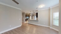This single-story, 3-bedroom, 2-bathroom residence offers a thoughtfully designed open-concept layout that seamlessly connects the living room and kitchen. The living and dining area features light hardwood-style flooring, crown molding, and a ceiling fan, creating a bright and welcoming atmosphere. Large windows allow natural light to fill the space, enhancing the neutral, warm-toned walls throughout.

The kitchen is well-equipped with rich dark wood cabinetry, granite countertops, a subway tile backsplash, stainless steel appliances including a range and microwave, and a breakfast bar peninsula accented by sleek pendant lighting. Track lighting overhead adds additional illumination to the functional workspace.

The spacious primary bedroom provides a comfortable retreat, complete with crown molding, a ceiling fan, and a window overlooking greenery outside. A dedicated walk-in closet outfitted with wire shelving offers ample storage. The bathrooms are clean and modern, with one featuring a glass-enclosed walk-in shower with white tile surround and a brushed nickel frame.

Additional highlights include three hallways for easy navigation, a dedicated laundry room, and consistent hardwood-style flooring throughout. The overall aesthetic is cohesive and move-in ready, combining practical functionality with tasteful, contemporary design elements.