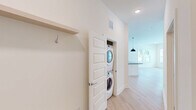 Located at 5111 Abercorn St in Savannah, GA, this well-appointed 2-bedroom, 2-bathroom home offers a thoughtfully designed single-floor layout with a clean, modern aesthetic. The open-concept kitchen and living area serves as the heart of the home, featuring light hardwood-style flooring, recessed lighting, and a central island with a dark granite countertop and undermount sink, illuminated by two sleek pendant lights. The kitchen is equipped with stainless steel appliances, warm wood upper cabinetry, white lower cabinets, and a tile backsplash, with a glazed door providing natural light from outside. The living area extends comfortably from the kitchen, creating an inviting, open atmosphere. Both bedrooms feature soft carpet flooring, generous proportions, and ample natural light from large windows with blinds. The primary bedroom benefits from a ceiling fan and an en-suite bathroom, while a walk-in closet with wire shelving provides practical storage. The bathrooms feature dark granite vanity countertops and clean, bright finishes. A dedicated in-unit laundry closet with a stacked washer and dryer adds everyday convenience, and a hallway coat hook and shelf offer functional entryway storage throughout this well-designed Savannah residence.