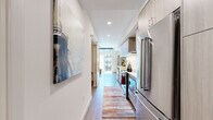 Located in Redmond, WA, this thoughtfully designed one-bedroom, one-bathroom residence offers a modern aesthetic with high-quality finishes throughout. The galley-style kitchen is a standout feature, outfitted with stainless steel appliances including a French door refrigerator, built-in microwave, electric range with a stainless hood, and a subway tile backsplash. Light wood cabinetry and white quartz countertops lend a clean, contemporary feel, while hardwood-style flooring runs seamlessly throughout the space. A hallway adorned with statement wall art connects the kitchen to the living area, where large sliding glass doors flood the room with natural light and open to a private balcony with courtyard views. The living room also features a wall-mounted mini-split system for year-round comfort. The bedroom is a cozy retreat with a sliding barn-style closet door revealing a walk-in closet, complemented by warm neutral tones and soft wall art. The bathroom features a full tub-shower combination with crisp white subway tile surround. Recessed lighting and a cohesive modern design palette tie every room together, making this a well-appointed urban residence in the heart of Redmond.