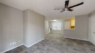 This single-floor residence offers a cohesive, modern aesthetic defined by light wood-look flooring that flows seamlessly throughout every room. Neutral gray-toned walls and white trim create a clean, bright backdrop, while textured ceilings add a subtle architectural detail overhead.

The open living area is anchored by a ceiling fan with integrated lighting, providing both comfort and illumination. Natural light filters in through blinded windows, lending a welcoming ambiance to the space. The layout connects the living area directly to the kitchen, which is separated by a peninsula-style breakfast bar. The kitchen is well-equipped with white shaker cabinetry, granite-patterned countertops, stainless steel appliances including a refrigerator and dishwasher, and a tile backsplash that adds a decorative touch.

The bedrooms are comfortably sized, each featuring the same wood-look flooring, ceiling fans, and windows with blinds that allow for natural light and privacy. A hallway connects the private areas of the residence with ease.

The bathroom is finished with large white subway tiles in the shower-tub combination, a granite-top vanity with white cabinetry, and wood-look flooring, creating a crisp, contemporary feel. Overall, the space presents a thoughtfully updated interior with consistent finishes and a functional, practical layout.
