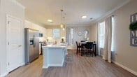 Located on Wendwood Lane in Charlotte's 28211 zip code, this single-story residence presents a well-designed, open-concept layout with contemporary finishes throughout. The kitchen serves as a central highlight, showcasing white shaker cabinetry, quartz countertops, a subway tile backsplash, and a full suite of stainless steel appliances including a gas range, microwave, refrigerator, and dishwasher. A substantial central island with pendant lighting above provides bar seating and flows naturally into the dining area, where large windows allow generous natural light to fill the space. Light-toned wood-style flooring runs through the main living areas, complementing the neutral color palette.

The living room features crown molding, a ceiling fan, and an open sightline to adjacent spaces, creating a cohesive and airy feel. The dining nook benefits from additional window views. Bedrooms are carpeted for comfort, each offering ceiling fans and windows with outdoor views. The primary bathroom includes a wide vanity with white cabinetry, quartz countertops, a soaking tub, and access to a walk-in closet. A secondary bathroom mirrors the clean aesthetic with a white vanity and tub-shower combination. In-unit laundry access adds further practicality to this well-appointed residence.