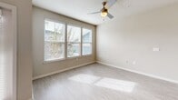 Located at 201 Kenbrook Way in Davenport, Florida, this single-floor residence offers a clean, modern aesthetic with a practical and comfortable layout. The open-concept kitchen and living area serves as the heart of the home, featuring light wood-look tile flooring, large windows with blinds that invite generous natural light, and a ceiling-mounted light fixture. The kitchen is a standout, outfitted with dark wood-grain cabinetry, white quartz countertops, a curved peninsula with an undermount sink, and a full suite of stainless steel appliances including a range, microwave, and refrigerator. Pendant lighting above the peninsula adds a contemporary touch. The bedroom offers plush carpeting, a ceiling fan, and windows with neighborhood views, creating a calm retreat. It connects directly to a full bathroom featuring a dark vanity with a white countertop, a large mirror, open floating shelves, tile flooring, and direct access to a walk-in closet complete with wire shelving. A dedicated utility room houses the in-unit washer and dryer. Throughout the residence, neutral tones, clean lines, and modern finishes create a cohesive and inviting living environment.