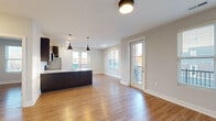 Located at 1011 Lusso Ave in Columbus, Ohio, this single-floor residence offers a well-designed, modern interior with a cohesive aesthetic throughout. The open-concept layout seamlessly connects the kitchen and living area, creating a spacious and functional living environment. The kitchen is a standout feature, equipped with dark espresso cabinetry, stainless steel appliances including a refrigerator, range, and microwave, a white quartz-topped island with an undermount sink, and a classic subway tile backsplash. Stylish pendant lighting above the island adds a contemporary touch. The living and dining area is bathed in natural light from multiple windows and a set of glass doors that open to a private balcony, offering views of the surrounding Columbus neighborhood. Warm hardwood-style flooring runs consistently throughout the unit, enhancing the sense of continuity. The bedrooms are well-proportioned, each featuring natural light from exterior-facing windows and ample closet space with double-door configurations. The bathroom is finished with a dark wood vanity, white quartz countertop, and a large mirror. Neutral gray walls and clean white trim provide a modern, move-in-ready finish throughout the entire space.