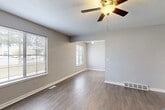 This multi-floor residence spans three levels and offers a thoughtfully designed layout with consistent finishes throughout. The main living areas feature smooth hardwood-style flooring in a warm gray-brown tone, complemented by neutral gray walls and crisp white trim. Ceiling fans with integrated lighting are present in the living spaces, promoting airflow and comfort. Multiple windows fitted with horizontal blinds allow natural light to filter through the open living and dining areas, which flow seamlessly into one another through an open passage.

The kitchen is outfitted with white shaker-style cabinetry, light-toned laminate countertops, and a double-basin sink, all set atop matching hardwood-style flooring. The clean, bright aesthetic makes the space both functional and welcoming.

The bedrooms are finished with plush wall-to-wall carpeting and feature ample natural light through large windows with blinds. Closet space is provided via double bi-fold doors, and the textured ceilings carry through consistently. A bathroom includes a full tub-shower combination with a clean white surround and a built-in niche.

Throughout the home, textured ceilings, clean white six-panel doors, and a cohesive neutral palette create a unified and move-in-ready atmosphere across all three floors.