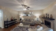 This single-story residence offers a well-organized layout across two bedrooms and two bathrooms, designed for comfortable everyday living. The living room serves as the focal point of the home, featuring rich hardwood-style flooring, a textured ceiling with a ceiling fan and light fixture, and warm neutral walls. A corner brick fireplace adds character and warmth, while a large decorative mirror mounted above the seating area enhances the sense of space. The room is well-lit with ambient lighting and benefits from natural light through slatted vertical blinds.

The kitchen is equipped with wooden cabinetry, granite-style countertops, and a black electric range, providing ample workspace and storage for everyday cooking needs.

Both bedrooms are carpeted and generously sized, each featuring multiple windows that allow for abundant natural light and outdoor views of surrounding greenery. Closet space is included in the bedrooms for practical storage. The bathrooms are finished with wooden vanities, granite-style countertops, and a tub-shower combination with clean white tile surrounds. Flooring in the bathrooms transitions to wood-style vinyl for easy maintenance. Overall, the home presents a cohesive, neutral aesthetic throughout.