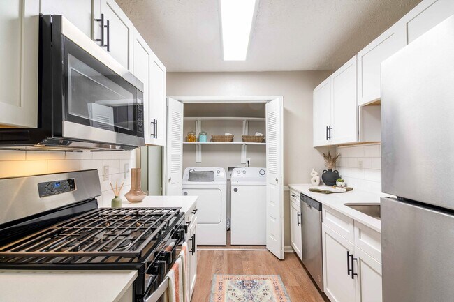 Cocina recién reformada con estufa de gas y lavadora y secadora en la vivienda. - Rosemont at East Cobb Apartments