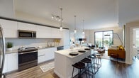 Located at 520 N Andrews Ave in Fort Lauderdale, this contemporary single-floor residence showcases a thoughtfully designed open-concept layout with high-end finishes throughout. The kitchen is a standout feature, equipped with sleek white flat-panel cabinetry extending to the ceiling, stainless steel appliances, a marble-style backsplash, and a generous island with quartz countertops and seating for multiple guests. Pendant lighting and a track system illuminate the space, which flows seamlessly into the living area. The living room is anchored by large sliding glass doors that open to a private balcony, filling the space with abundant natural light and offering outdoor views. Wood-style flooring runs throughout the main living areas, adding warmth to the modern aesthetic. The bedrooms are well-proportioned, each featuring large windows that invite natural light. The bathrooms are finished with marble-style tile flooring, backlit vanity mirrors, warm wood floating vanities, and walk-in closets nearby. A glass-enclosed shower is featured in the primary bath, reinforcing the spa-like atmosphere. The overall ambiance is clean, contemporary, and inviting.