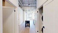 Located at 685 Richmond St in the heart of downtown London, Ontario, this modern 2-bedroom, 1-bathroom unit offers a well-designed open-concept layout with contemporary finishes throughout. Light hardwood-style flooring flows seamlessly across the entire space, complementing the bright, white walls and soaring exposed-ceiling design with visible industrial ductwork — a hallmark of loft-style architecture.

The kitchen is a standout feature, outfitted with sleek white cabinetry extending to the ceiling, stainless steel appliances including a range, over-the-range microwave, dishwasher, and refrigerator, as well as a marble-finish island countertop that anchors the space and provides additional prep and dining surface.

The bedrooms are bright and airy, benefiting from large black-framed windows that frame dynamic views of the downtown London skyline and streetscape, filling the rooms with natural light. A dedicated closet space provides practical in-unit storage.

The bathroom is finished in a clean, modern palette with large-format tile surround in the tub/shower combination, light wood-style flooring, and a minimalist white vanity. A convenient in-unit stacked washer and dryer is tucked neatly into a closet, adding everyday practicality to this stylish urban residence.