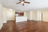 This single-floor residence offers a thoughtfully designed open-concept layout that seamlessly connects the kitchen, dining, and living areas. Rich hardwood flooring flows throughout the main living spaces, complemented by crown molding and ceiling fans that add a polished finish. The kitchen is a standout feature, showcasing warm cherry cabinetry, granite countertops with a tile backsplash, stainless steel appliances including a French door refrigerator, electric range, and built-in microwave, all centered around a spacious island with a sink and pendant lighting above. The generous living area is bathed in natural light from a wide bank of windows and glass doors that open to a balcony, with a ceiling fan overhead enhancing the airy feel. Two well-sized bedrooms feature plush carpeting, ceiling fans, and natural light from multiple windows, providing a comfortable retreat. Both bathrooms are finished consistently with cherry vanities, granite countertops, hardwood-style flooring, and framed mirrors. One bathroom includes a full soaking tub with a tiled surround and grab bars. The overall ambiance is clean, bright, and cohesive, with warm neutral tones and quality finishes throughout.